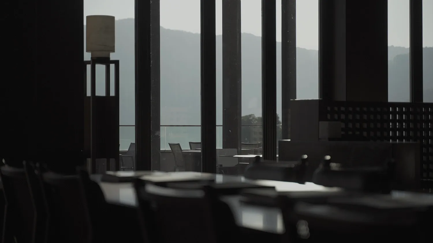 Empty modern restaurant with black glass and concrete bar, featuring sleek design and minimalist aesthetic.