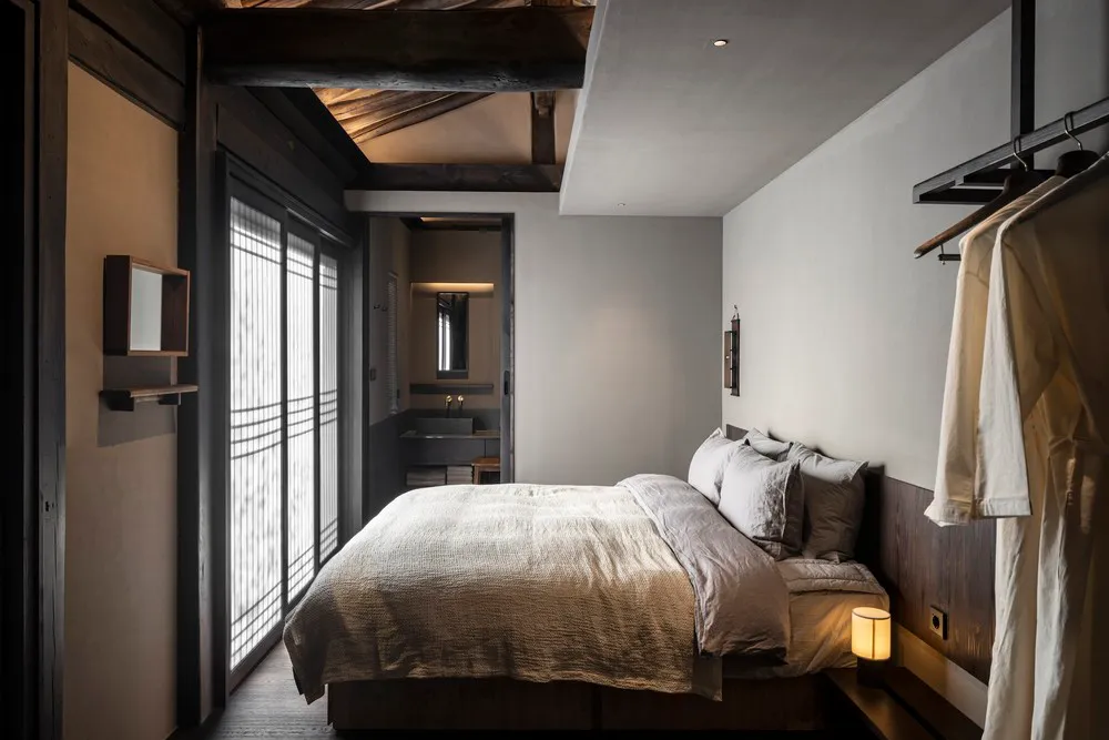 A minimalist bedroom featuring a wooden bed and clean, simple decor.