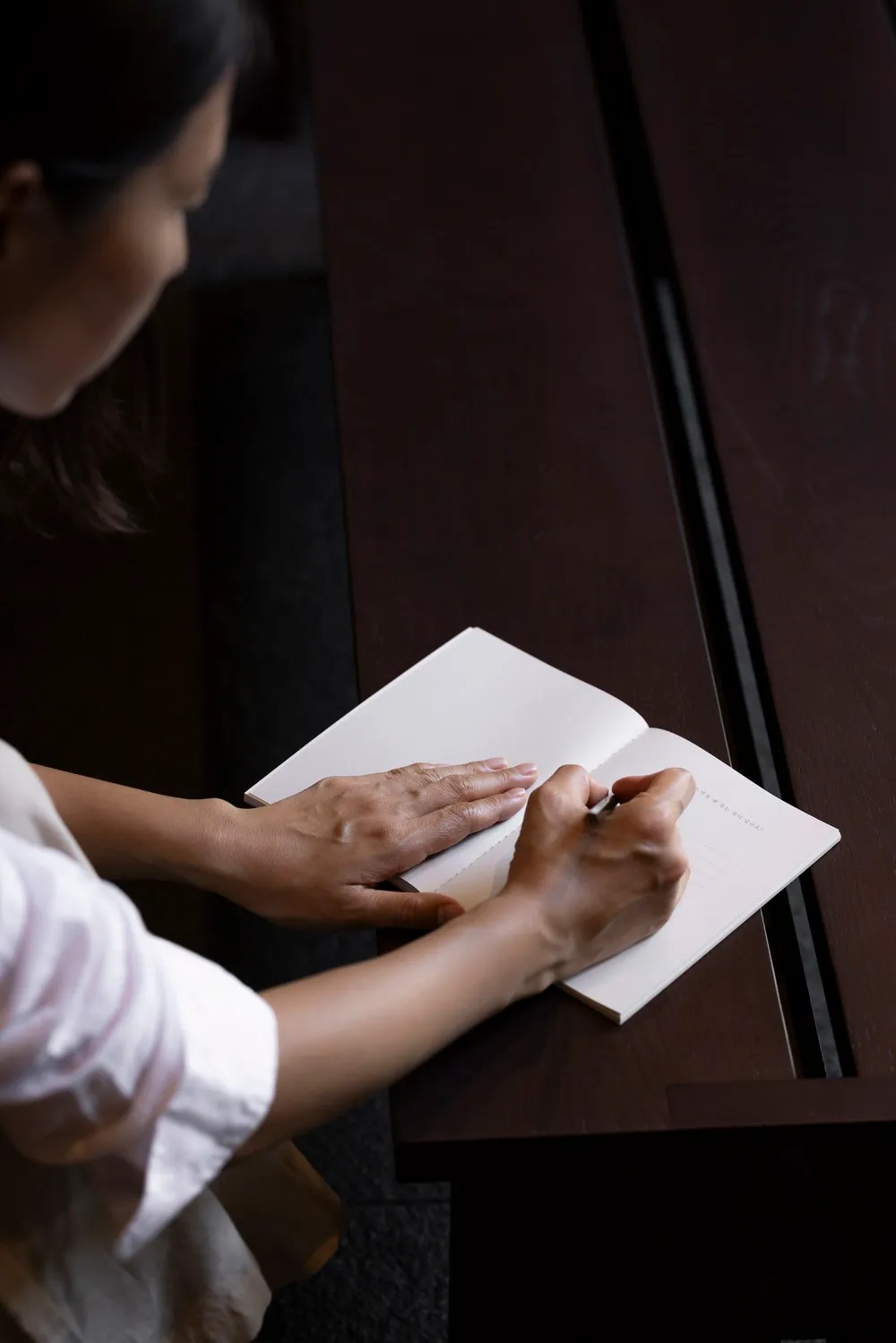 Person writing in a minimalist workspace using paper.