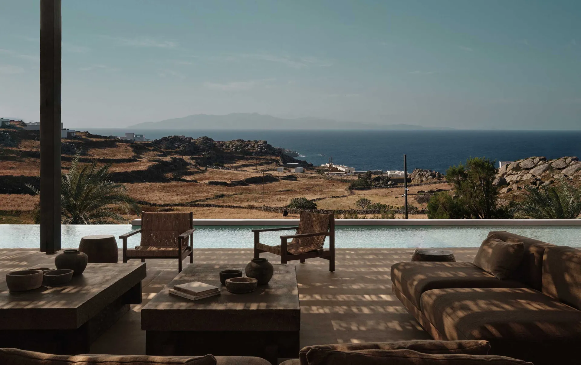 A minimalist residential patio with concrete and stone features overlooking the sea.