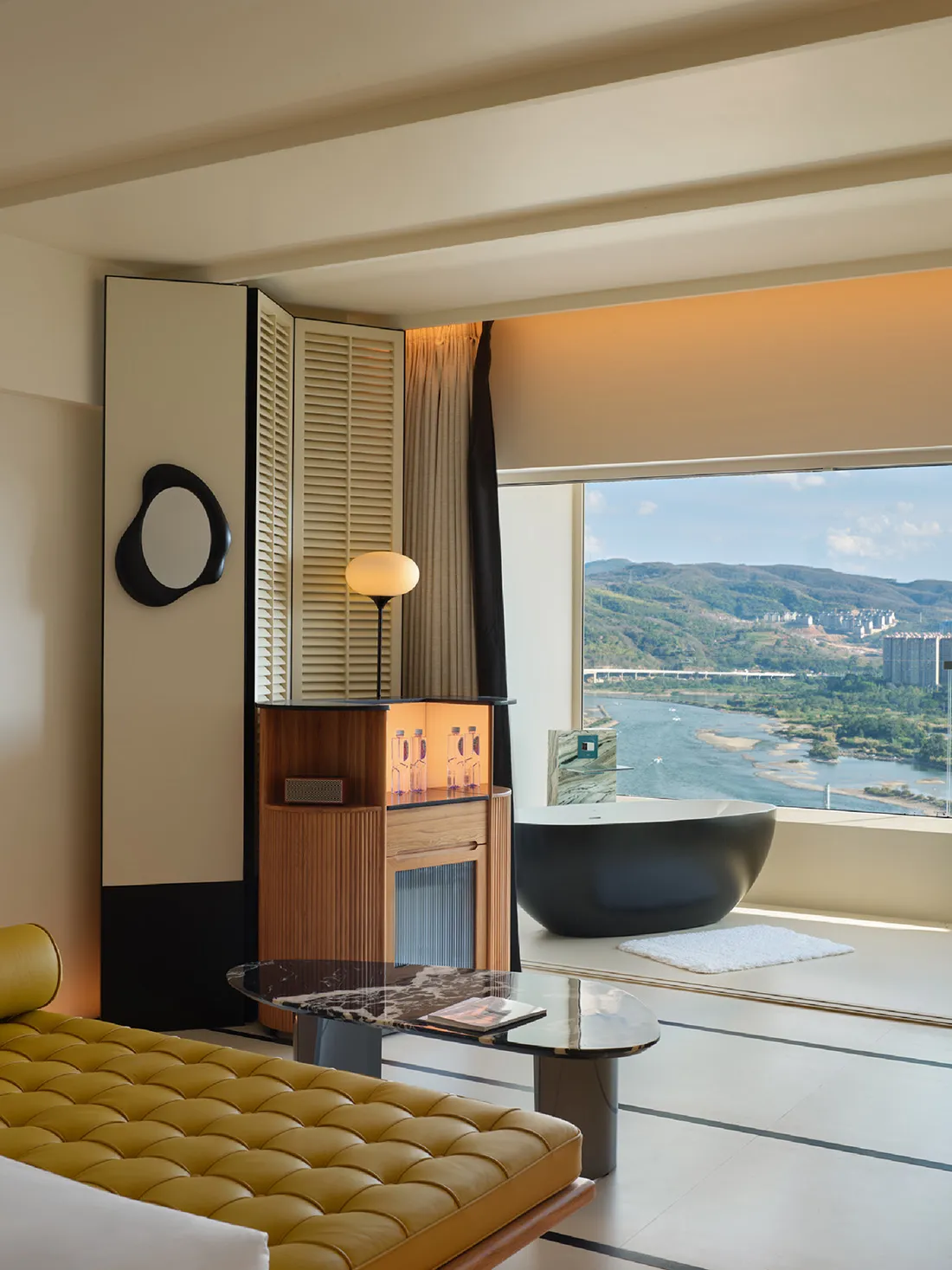 A minimalist residential suite featuring a floating bathtub and a stunning river view through large windows.