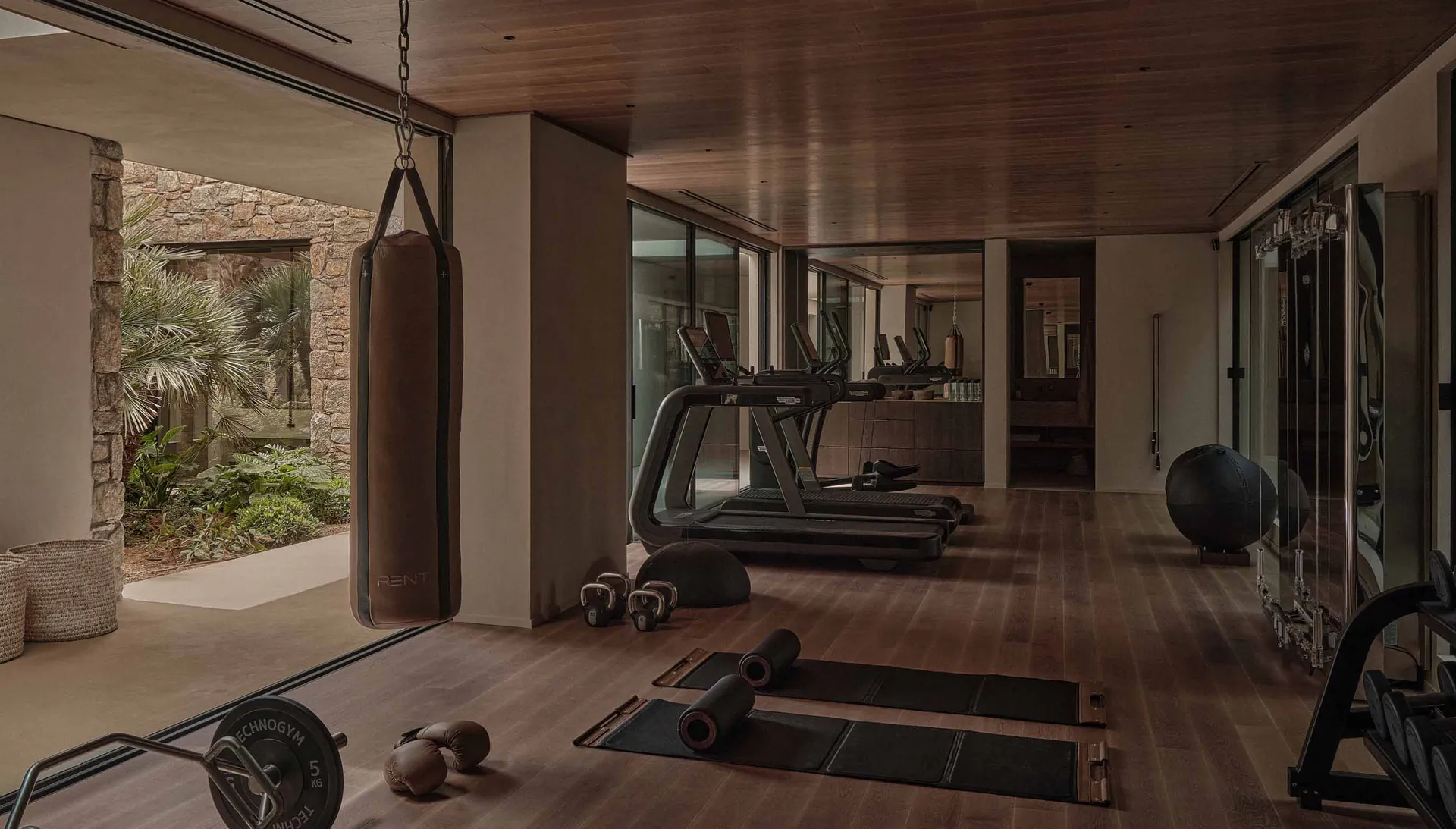 A modern indoor gym with a wooden floor and various workout equipment.
