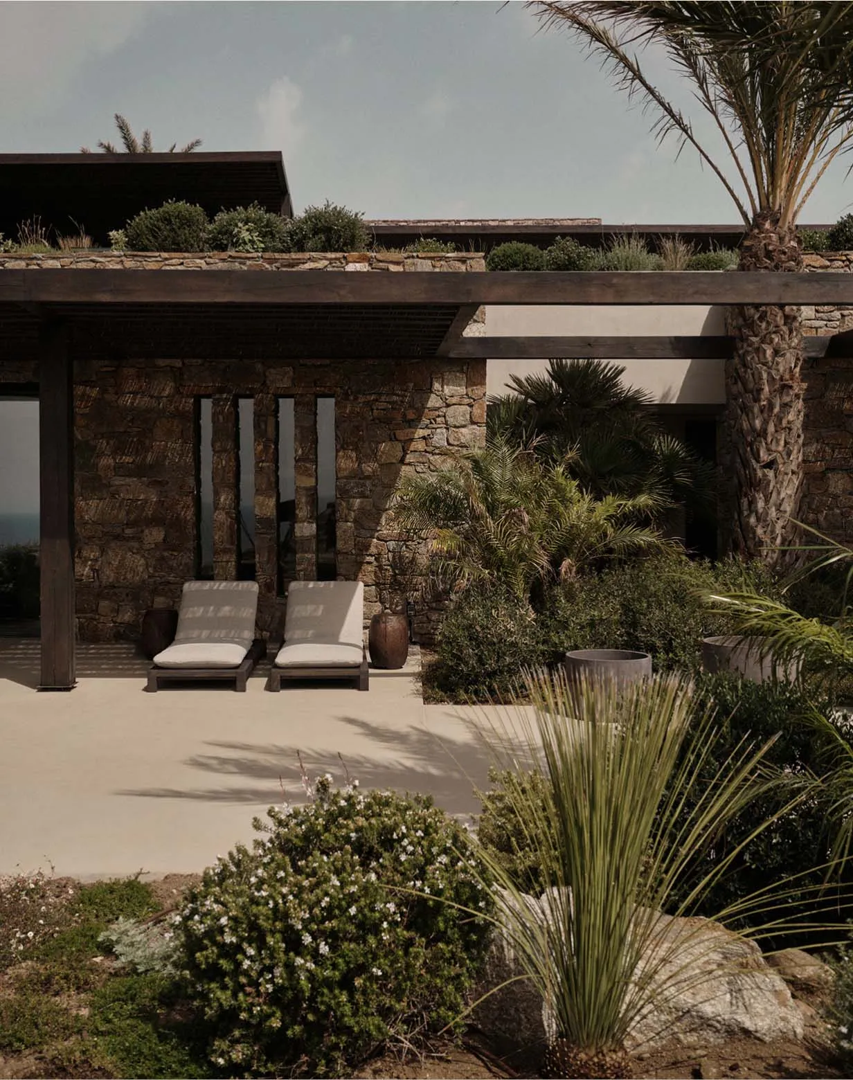 Modern house exterior with stone walls and concrete patio.