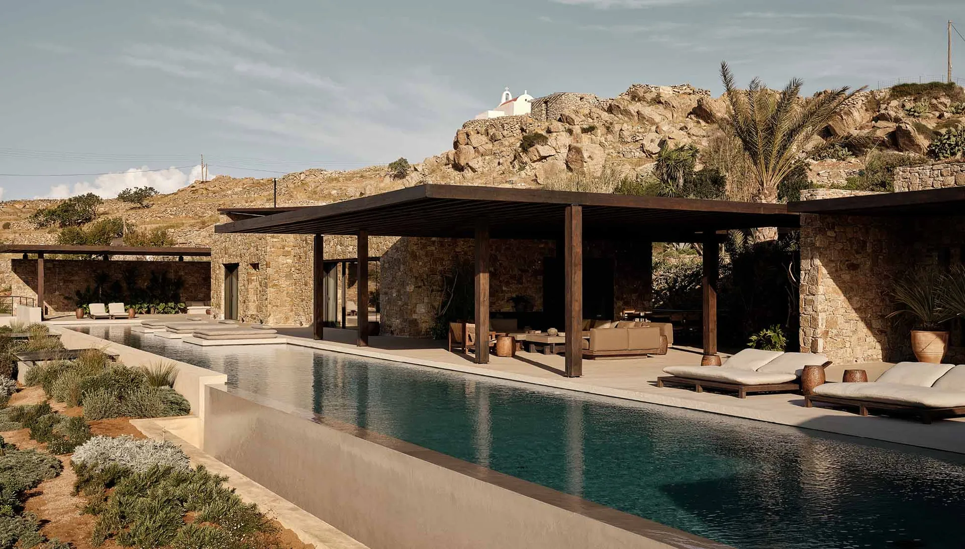 Modern villa with stone and concrete architecture and a stunning outdoor pool and patio area.