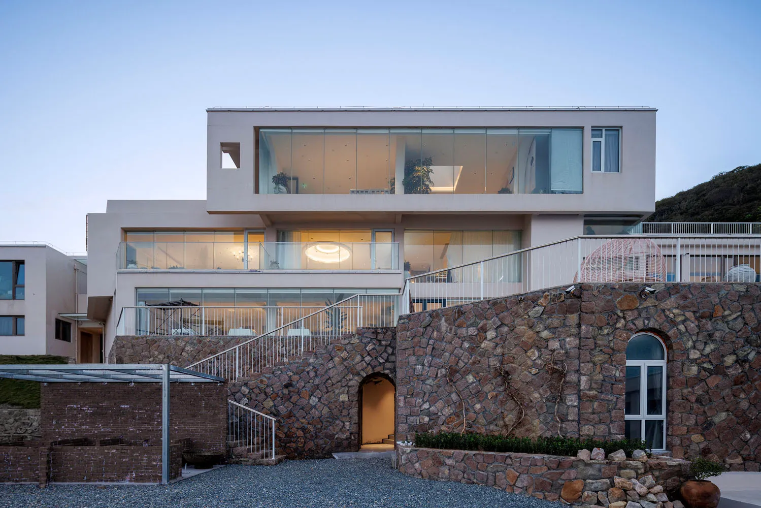 Modern house with white exterior, glass windows, and stone walls
