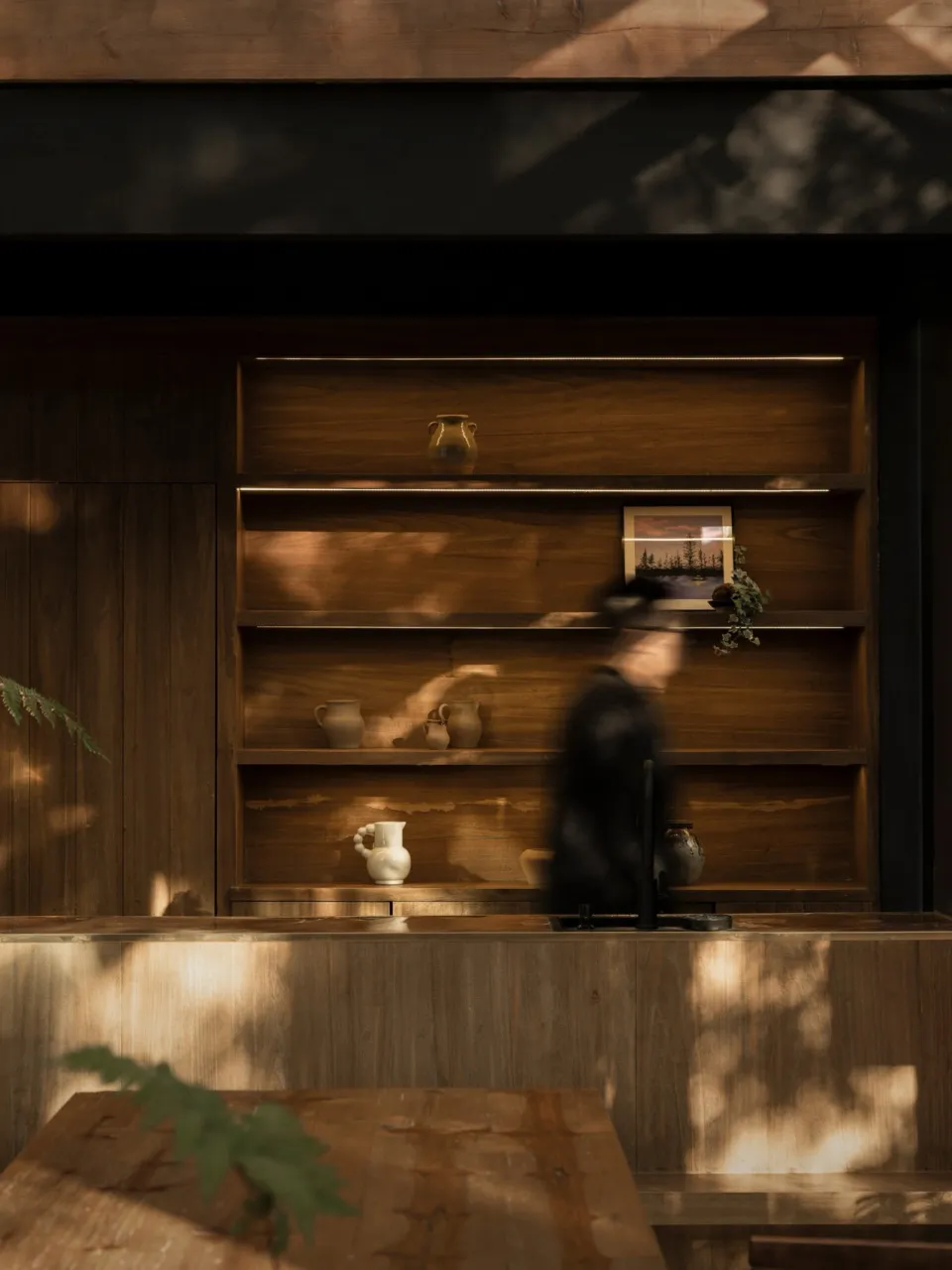 A modern kitchen with wooden shelves displaying various ceramic vessels.