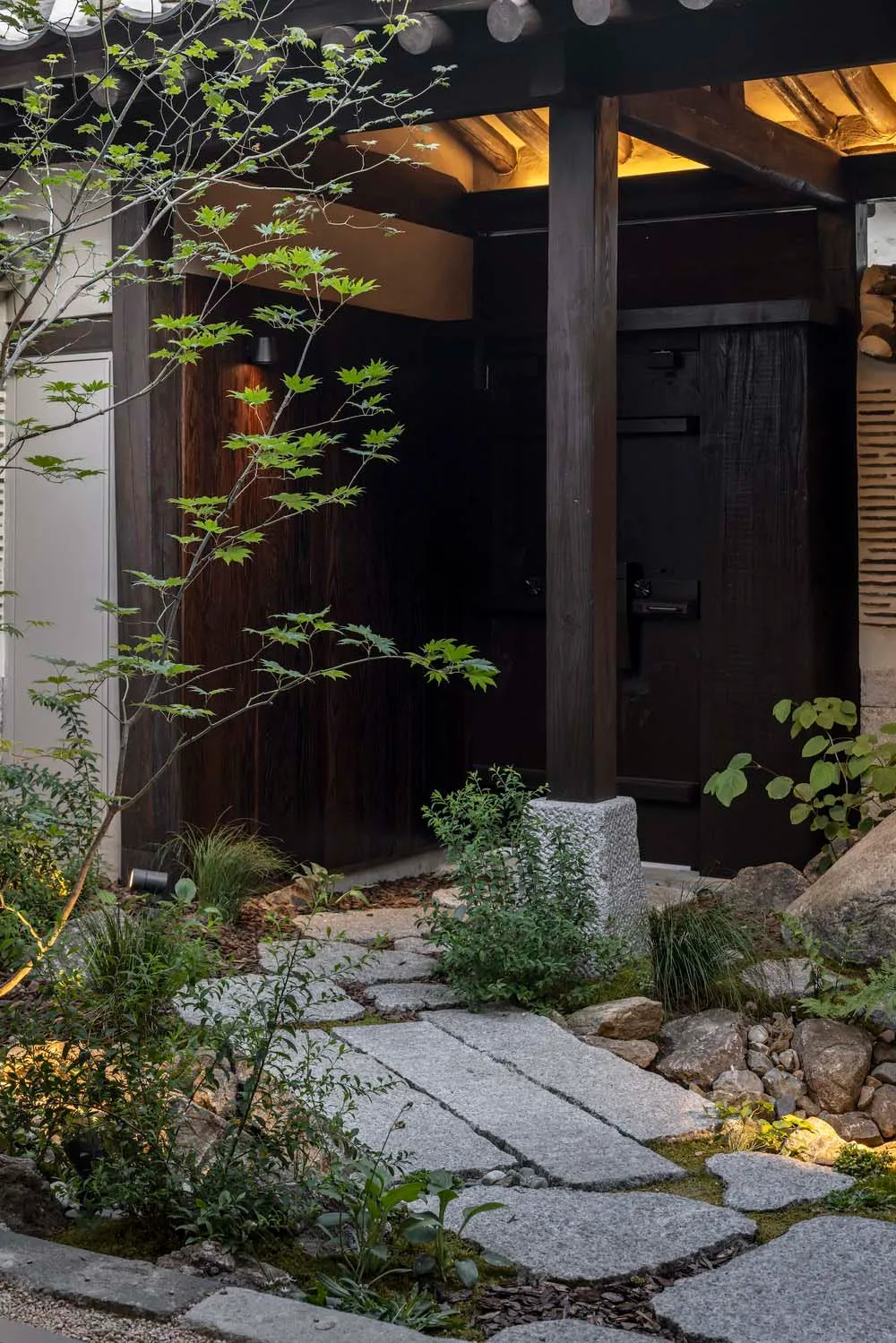 Stone pathway leading to wooden entrance with greenery