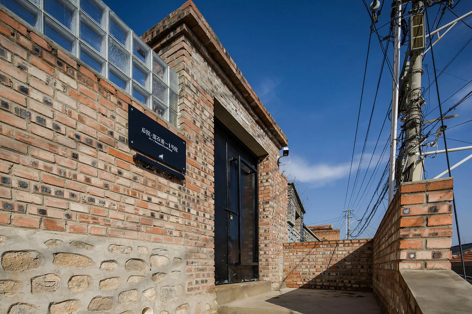 A brick building facade with a sign and a door.