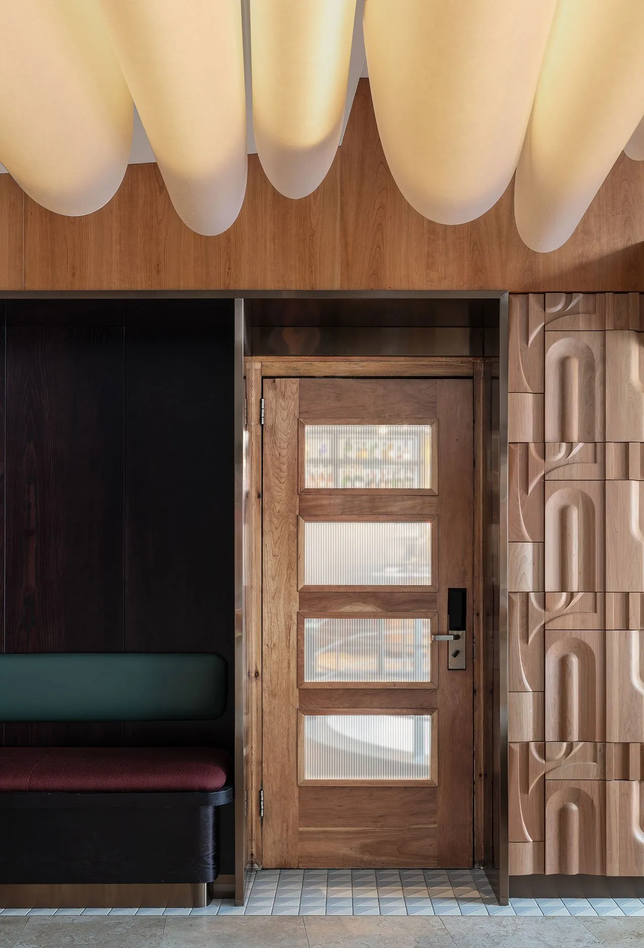 Modern wooden restaurant entrance with glass panels and bench seating.