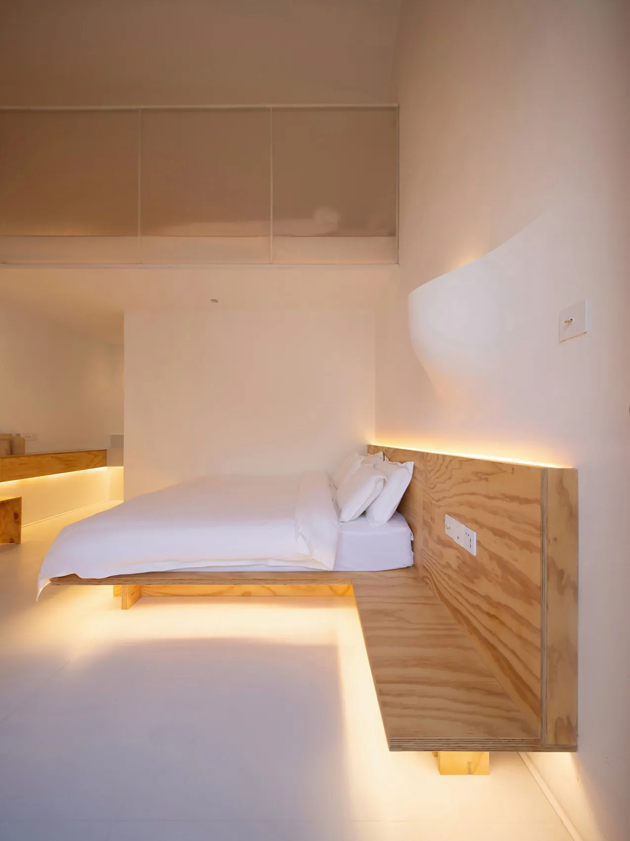 A modern minimalist bathroom with a white color scheme and wooden finishes.