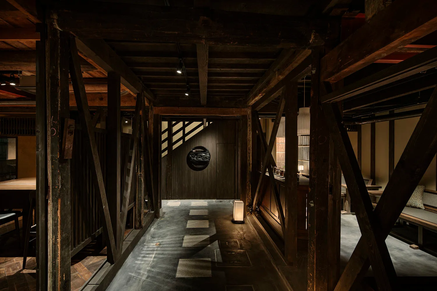 An industrial-style restaurant interior with a dark, wooden hallway leading to a seating area.