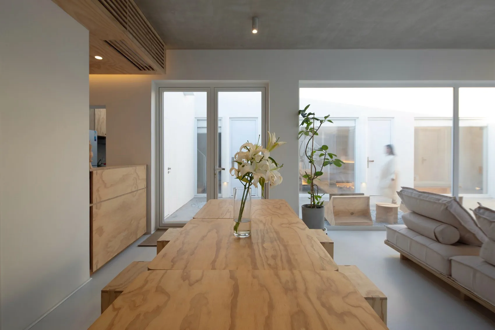 A minimalist living room with wooden furniture and a vase of flowers on the table.