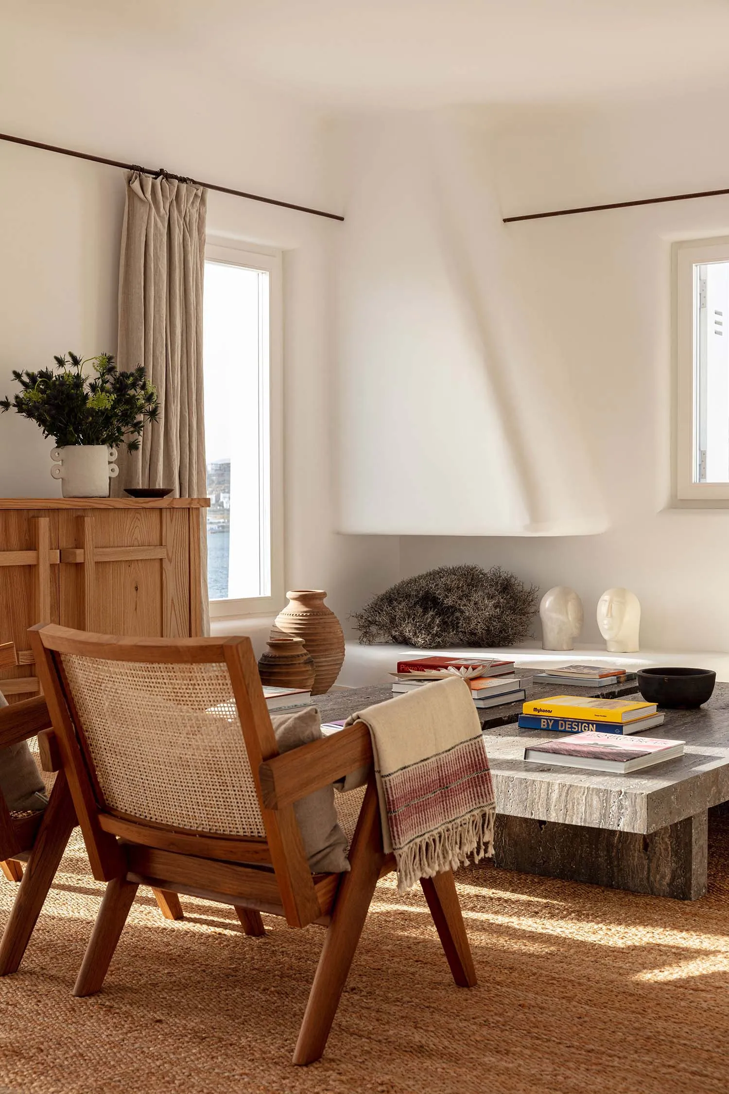 A modern living room featuring wooden furniture, a concrete coffee table, and a textured textile blanket.