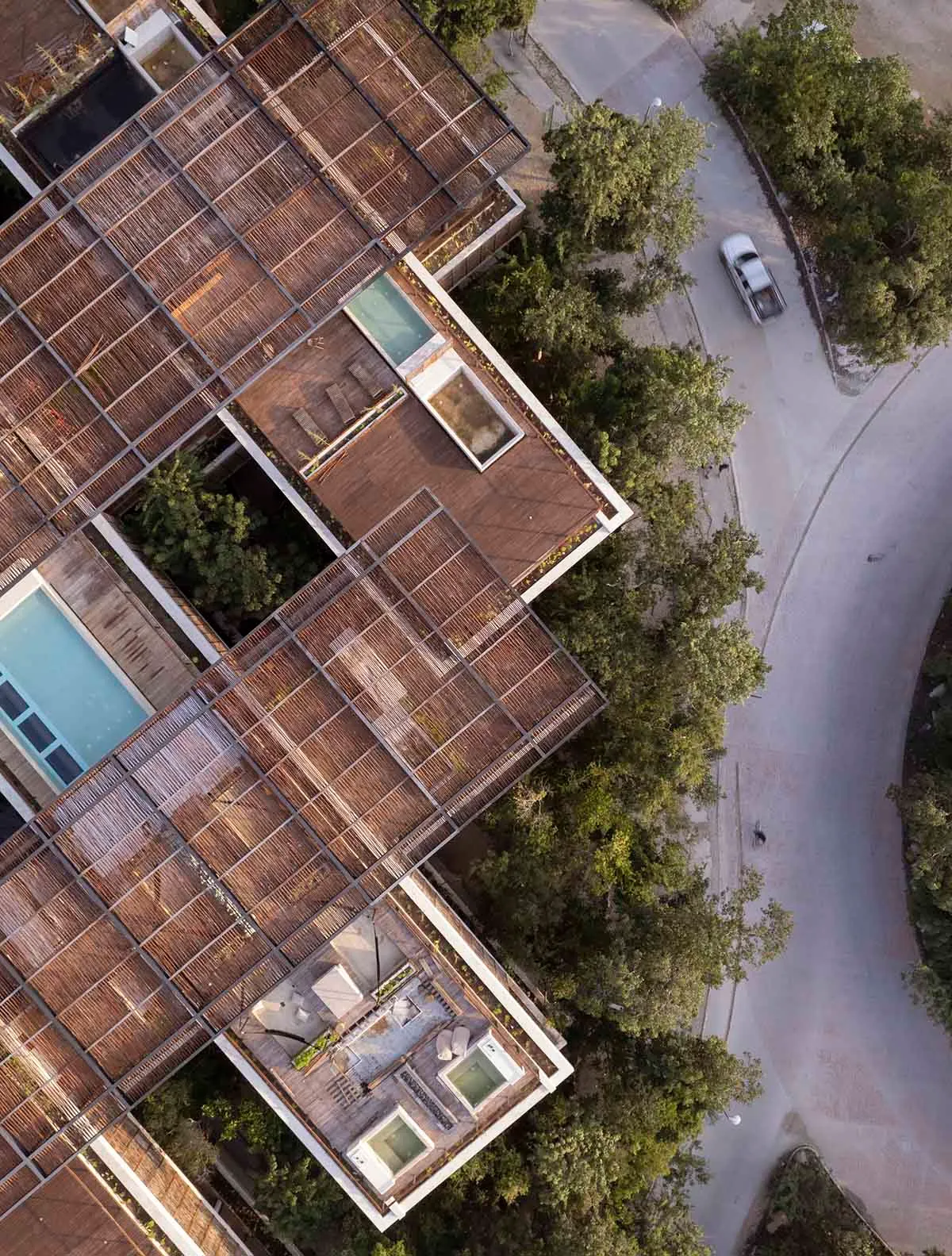Aerial view of a modern residential building with a wooden roof and rooftop terrace.