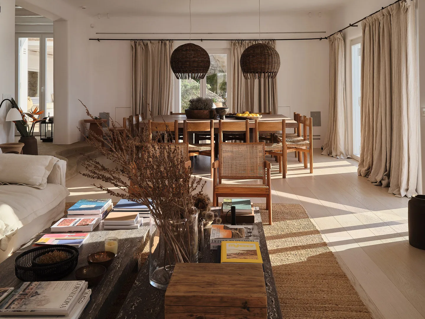 A living room with a neutral color palette and organic materials, featuring a wooden coffee table, a white sofa, and a hangin