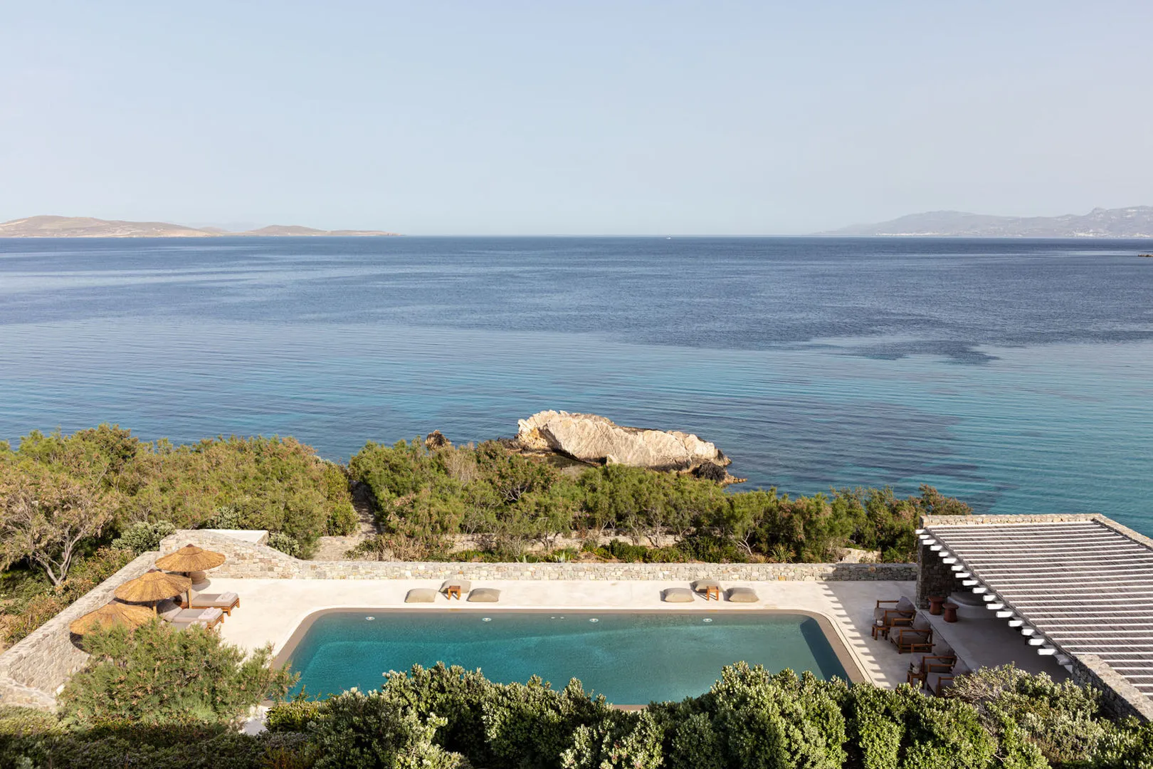 A vacation home with an outdoor living area featuring a hammock, lounge chairs, and a sea view.