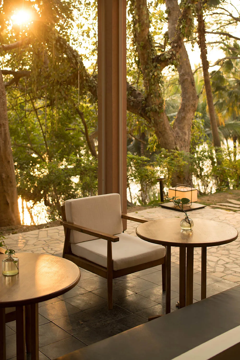 A cozy cafe featuring a wooden chair and tables with a serene outdoor view.