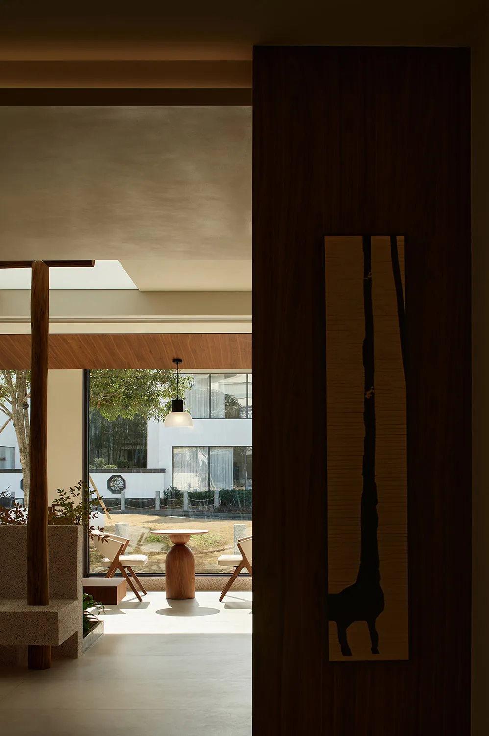 Interior space with minimalist design featuring glass windows, concrete flooring, and wooden elements.