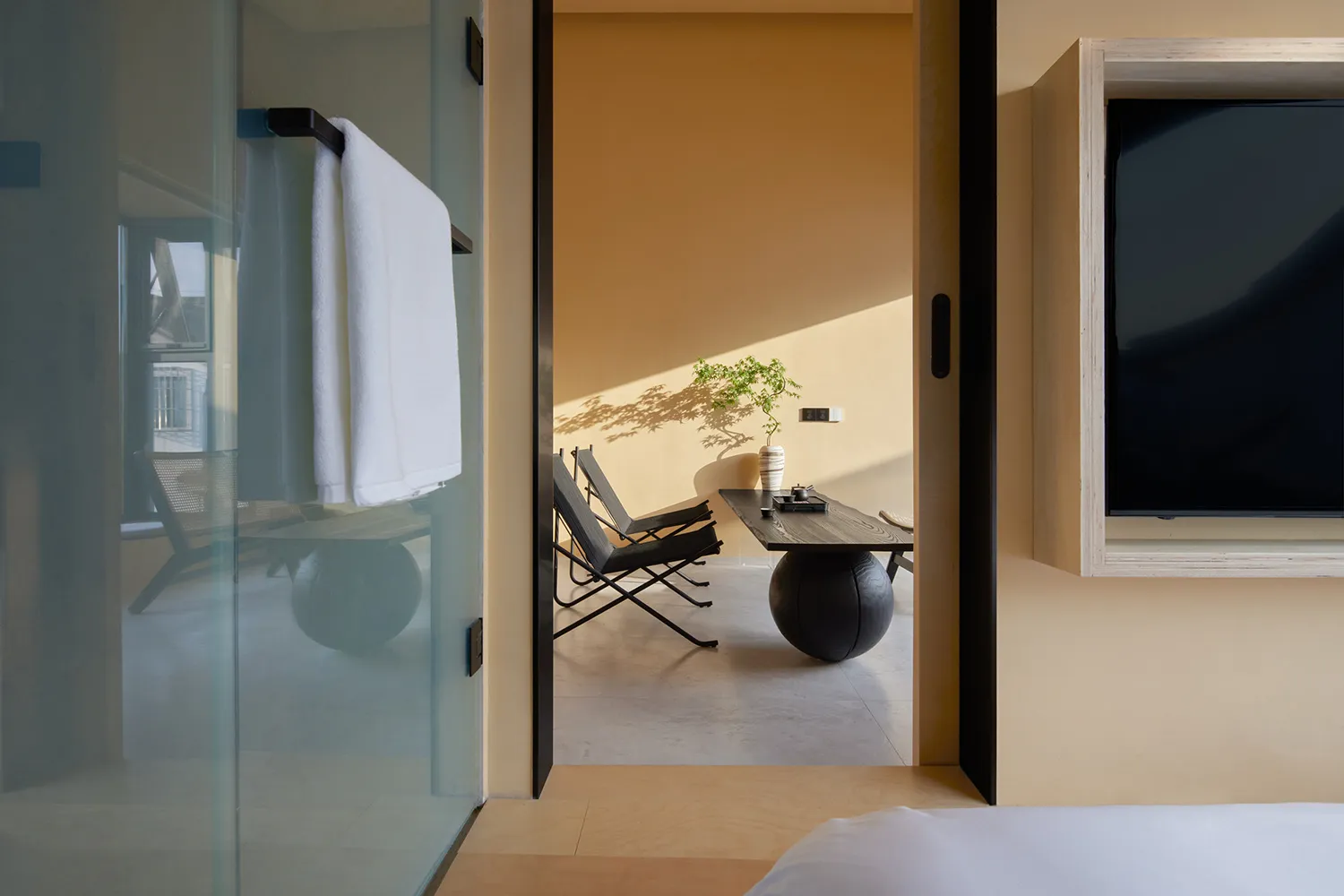 A minimalist living room featuring a wooden vase on a table with a potted plant and a comfortable seating area.