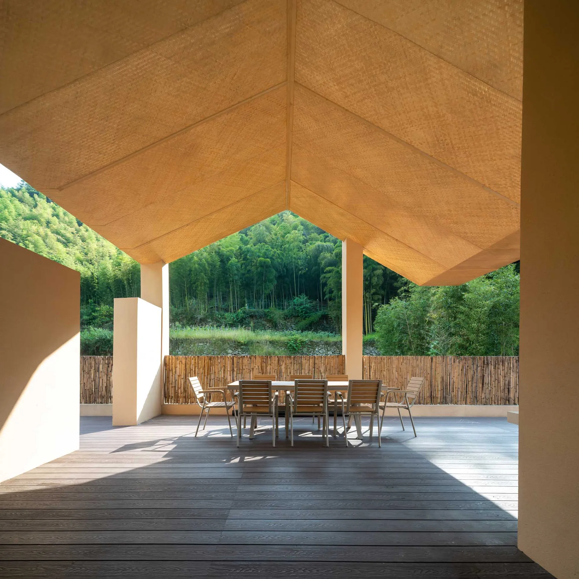 Outdoor patio with wooden floor and table surrounded by natural greenery.