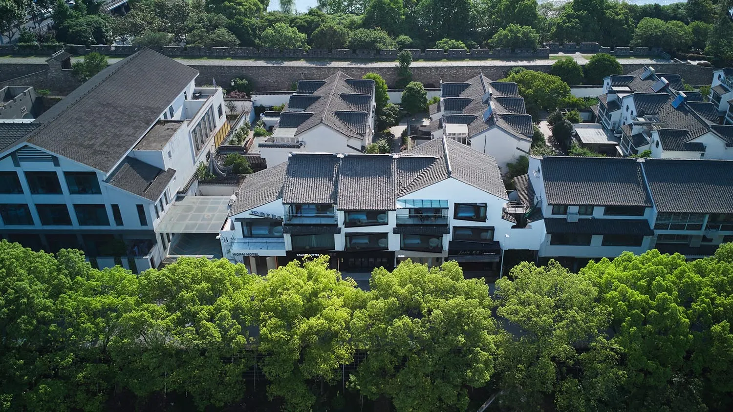 俯瞰傳統白色村落,灰瓦屋頂與綠葉樹木點綴其間。