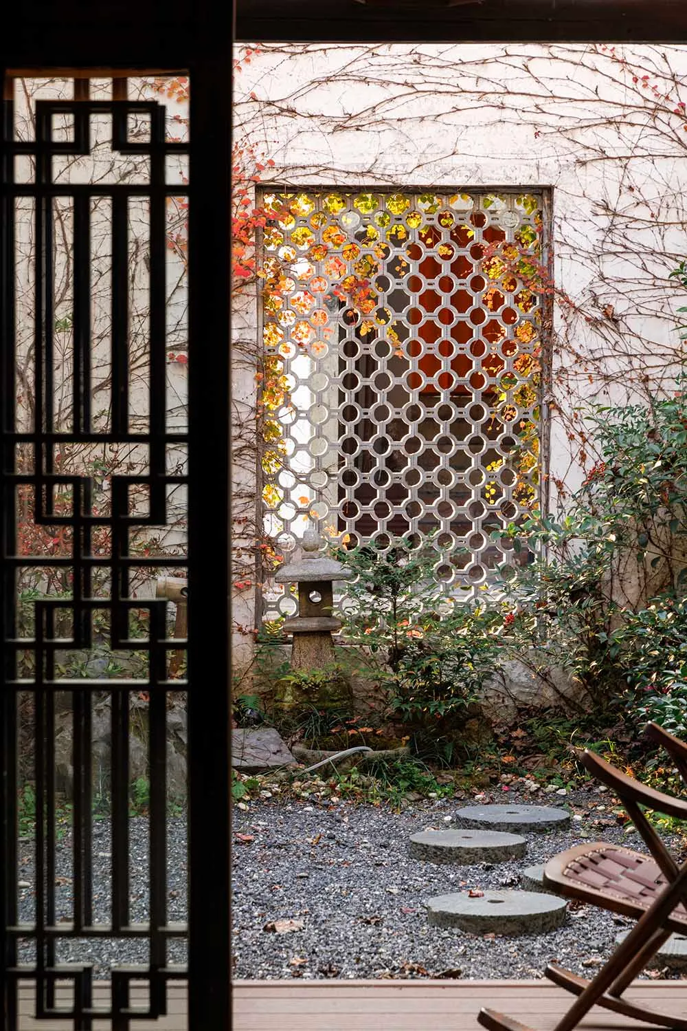 A serene garden scene featuring stone lanterns and wooden fencing, surrounded by wooden floors and stone pathways, with a ble