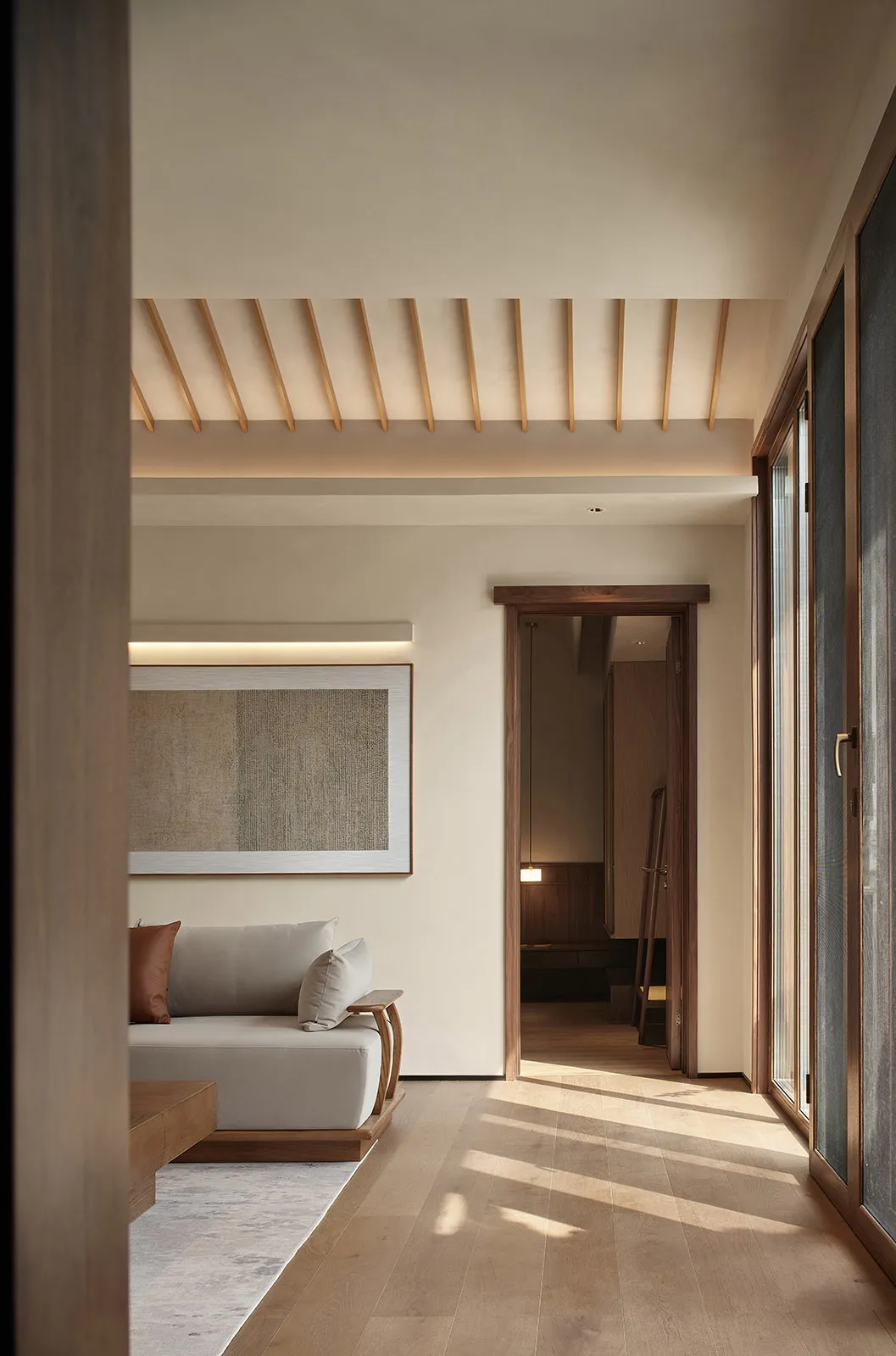 A minimalist living room featuring a comfortable seating area with a wooden sofa and pillows, complemented by a framed abstra