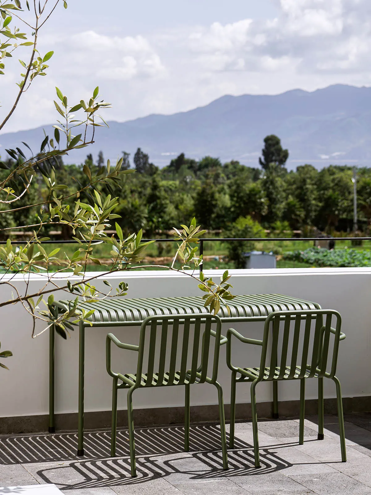 Metal outdoor furniture on a balcony overlooking a mountainous landscape.