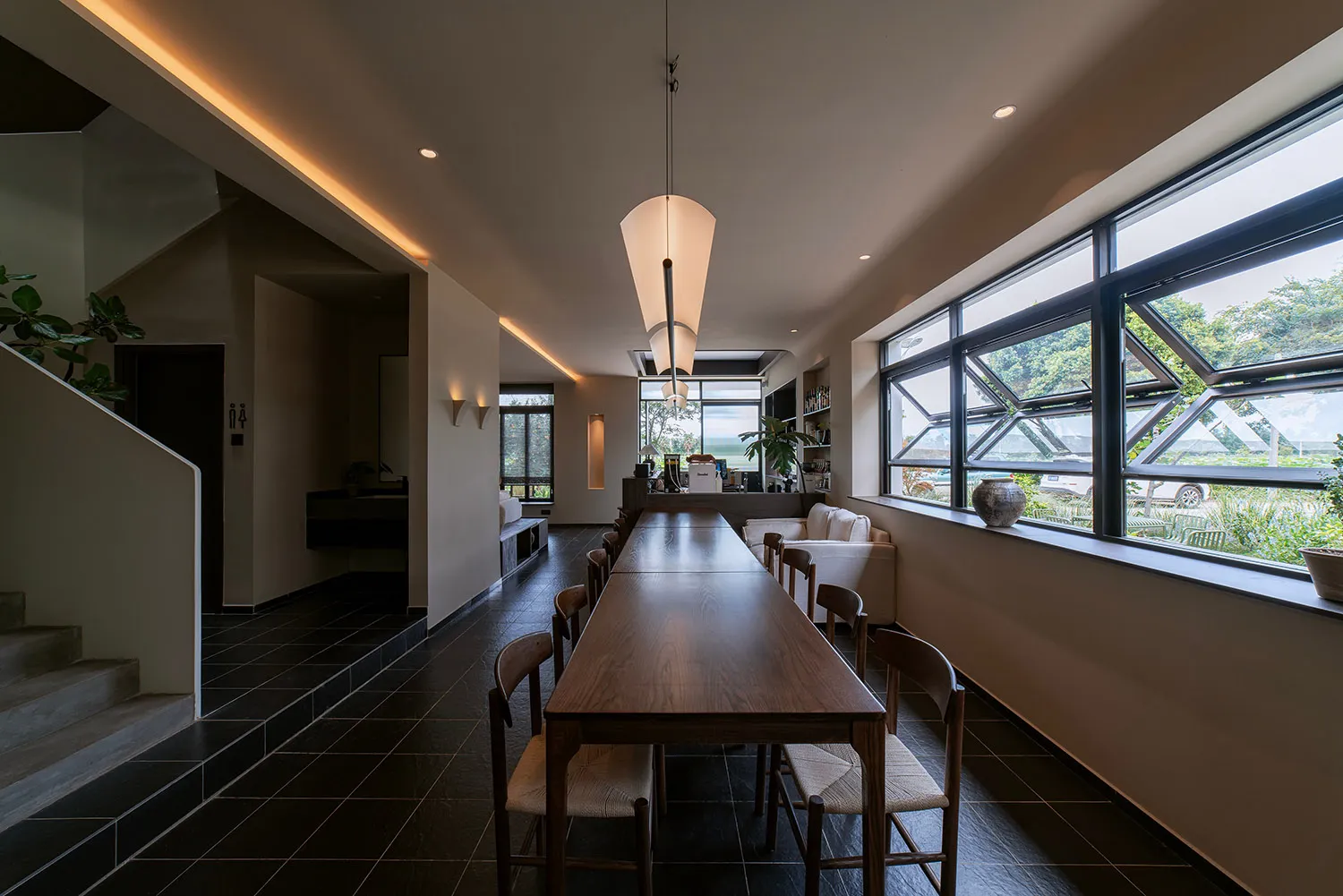 現代餐廳室內，木質餐桌、玻璃窗與混凝土地板。