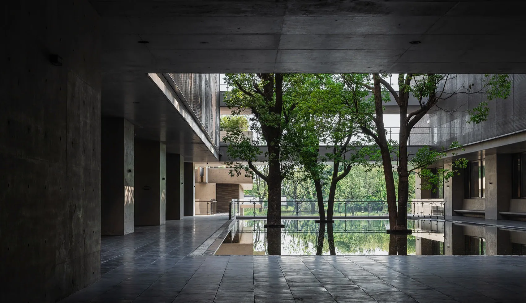 An interior space with modern design features, including concrete flooring and a large, open central area with a pool and tre