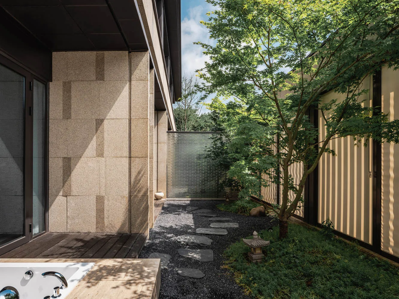 A minimalist patio featuring concrete slabs, gravel pathway, and wooden elements.
