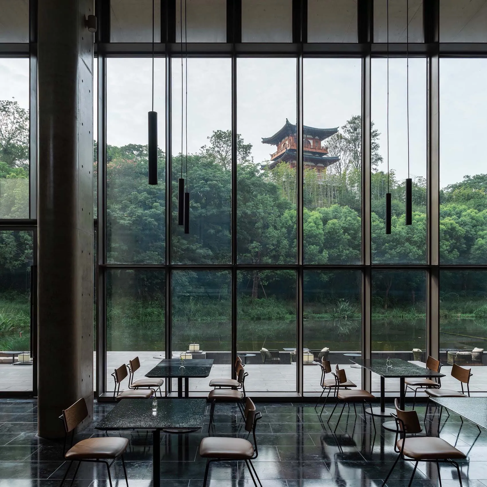 Modern restaurant interior with large glass windows and a concrete floor.
