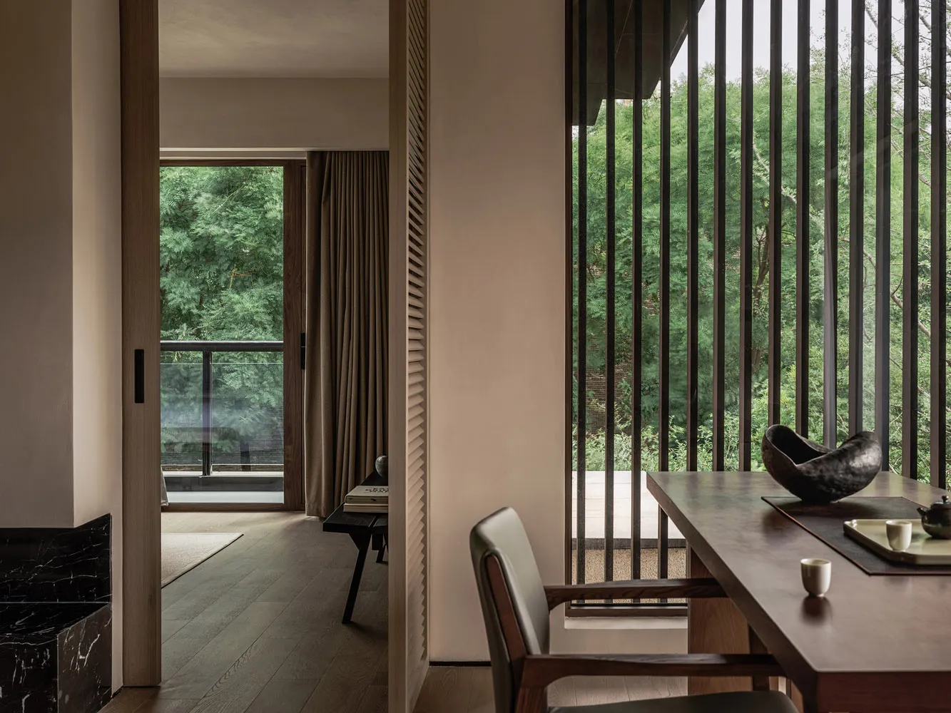 A minimalist residential interior design featuring wooden furniture and glass window panels.