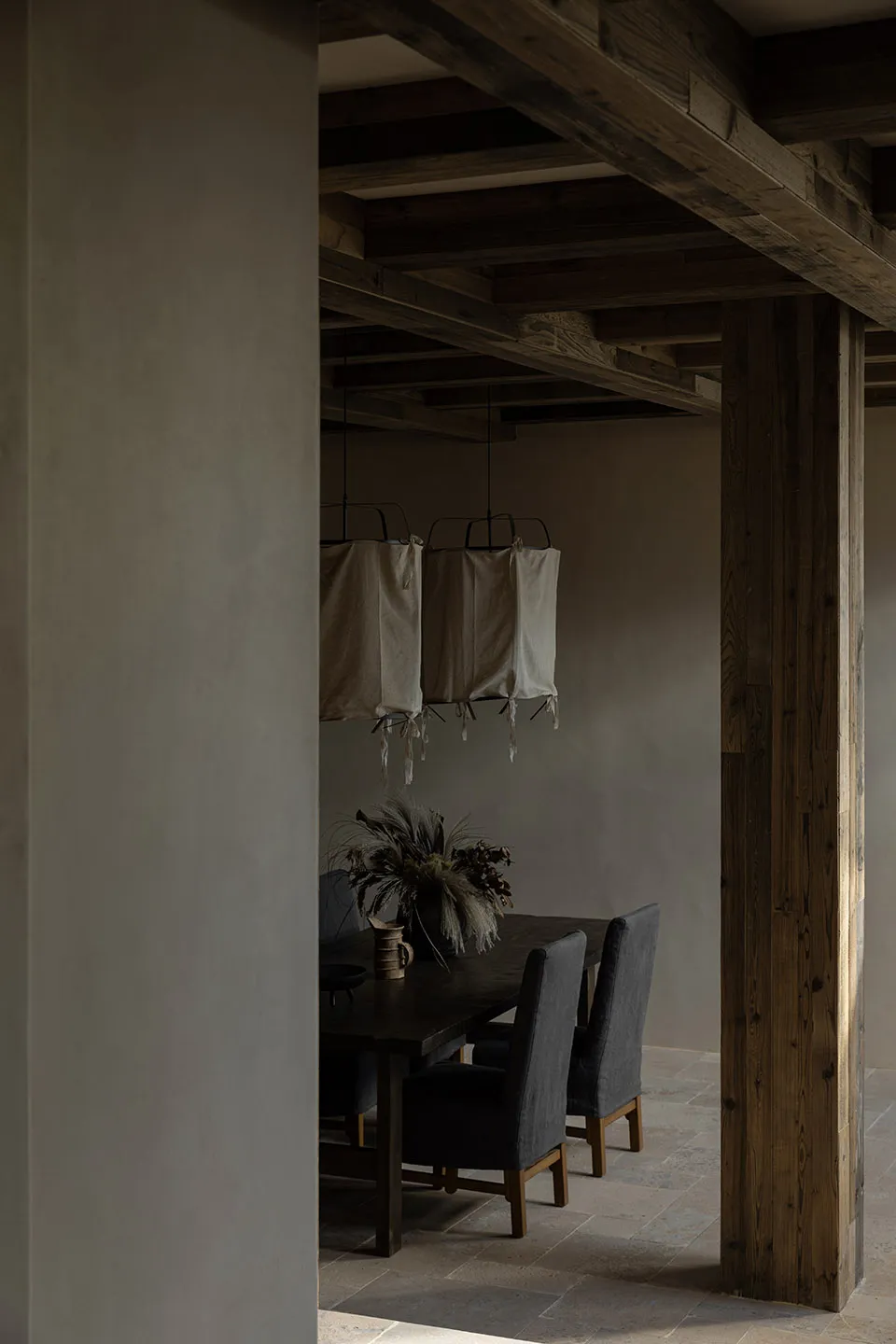 A minimalist dining room featuring wooden furniture and fabric lanterns hanging from the ceiling.