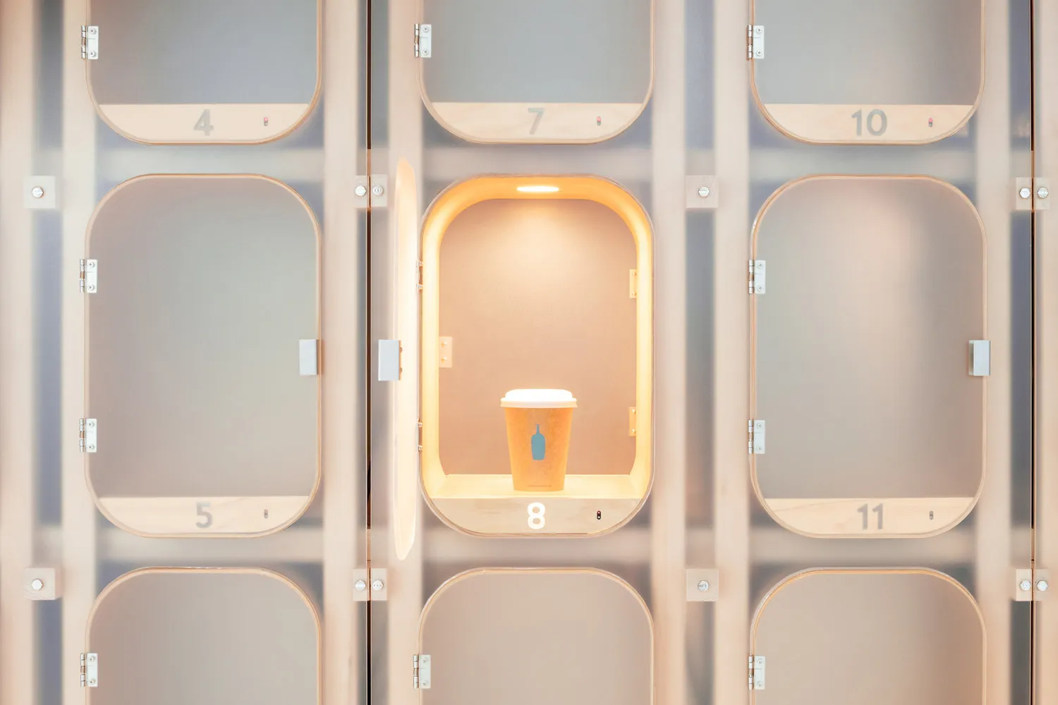 An open locker with a wooden wall and a lit cup inside, showcasing minimalist design in a technological setting.