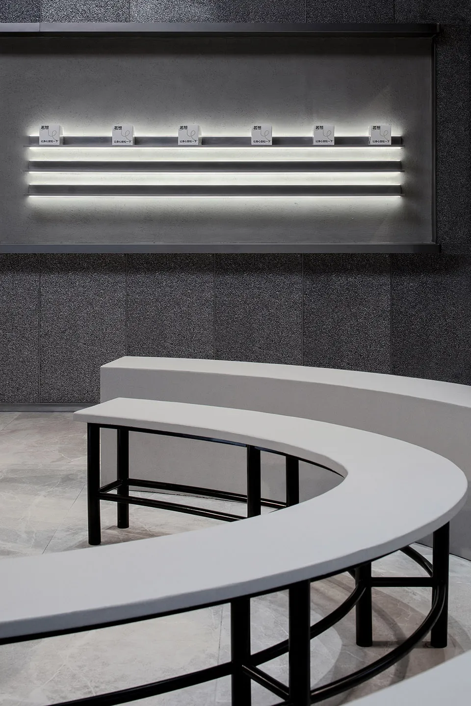 Modern minimalist interior with white benches and concrete floor and walls, illuminated by LED lighting, metal railings.