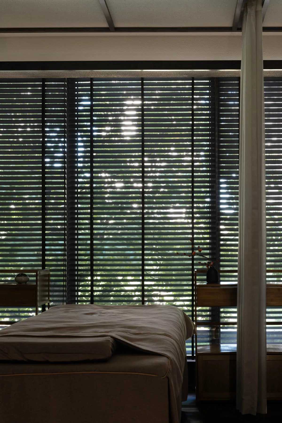 A minimalist bedroom with window blinds and a curtain.