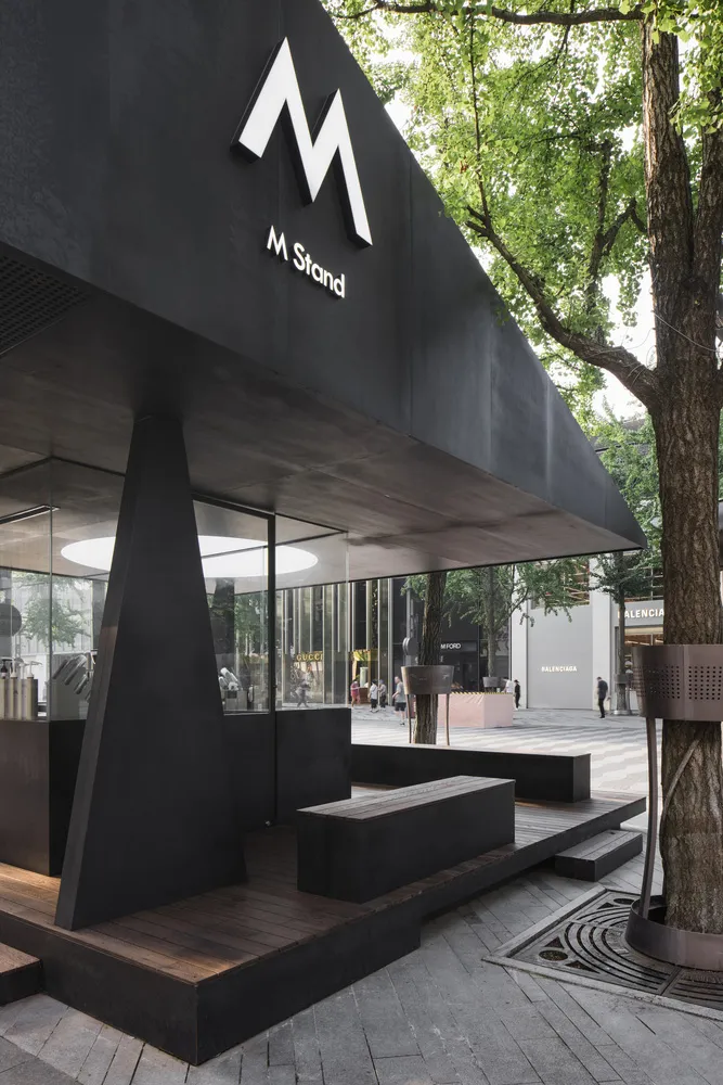 Modern, minimalist coffee shop exterior featuring concrete, glass, and wood materials.