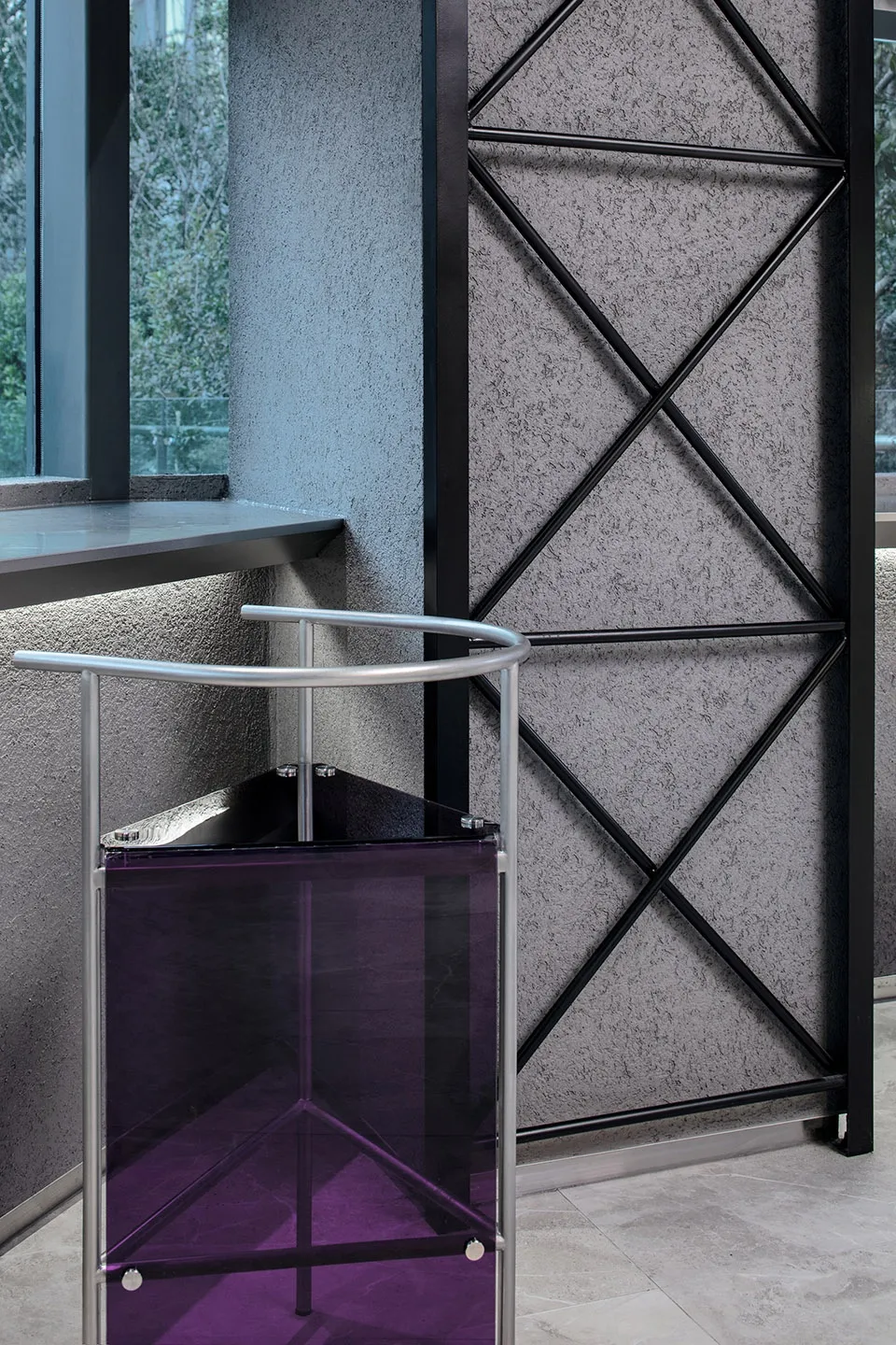 A metallic stool with a purple translucent seat in a minimalist interior space.