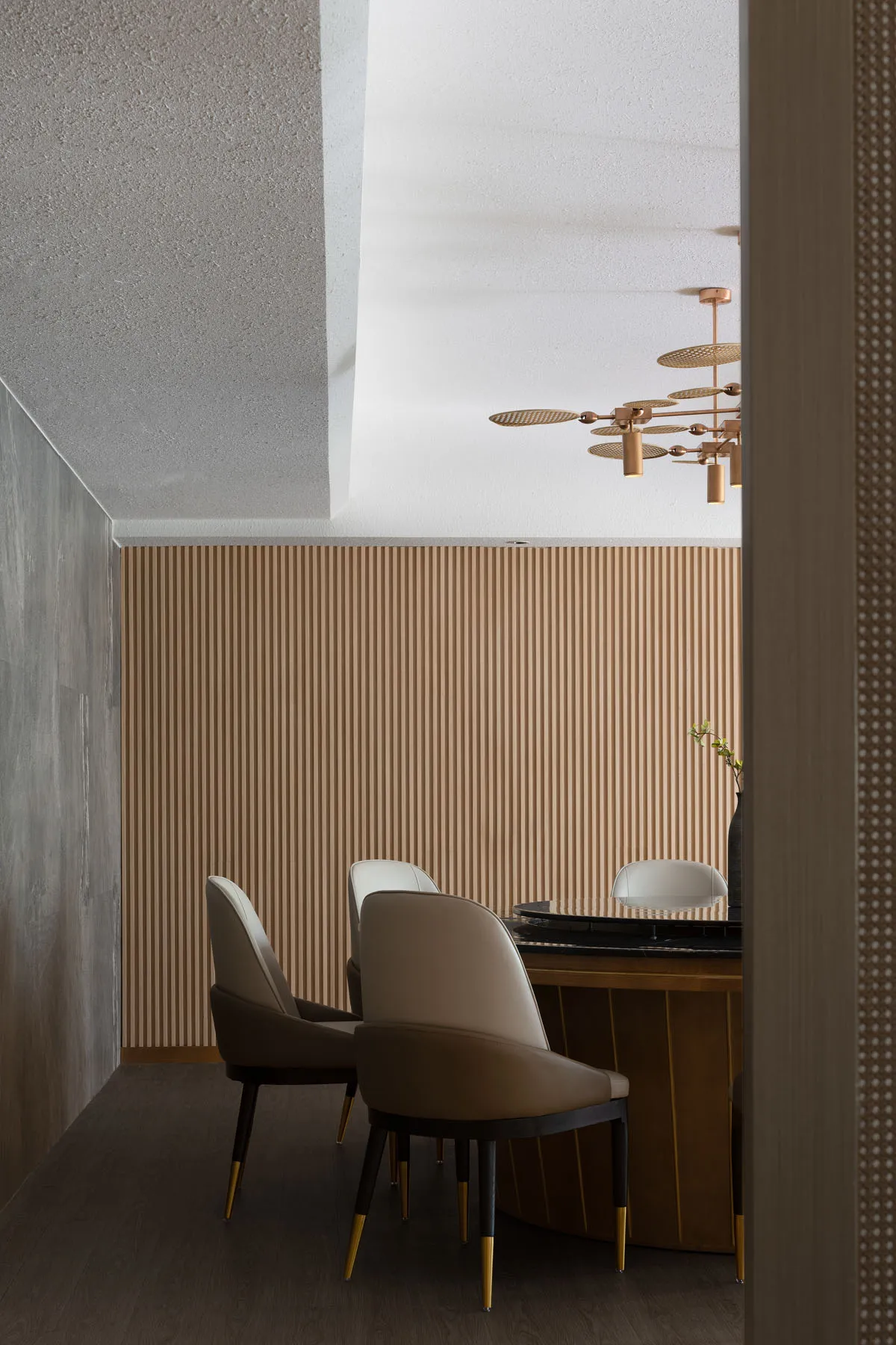 Minimalist dining room featuring modern chairs and a wooden table with a geometric chandelier.