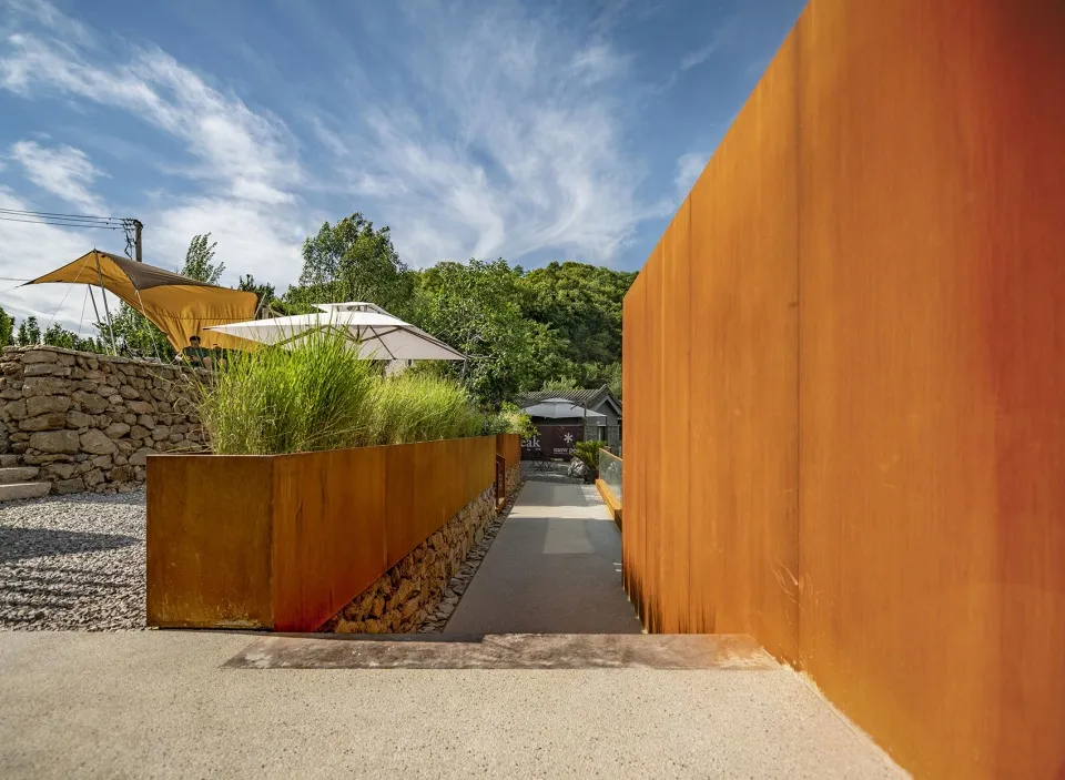 A minimalist landscape featuring metal curtain walls and a terraced garden.