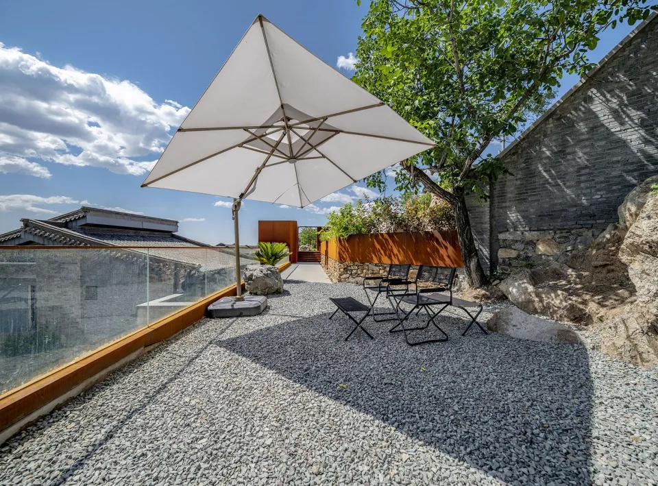 A modern patio featuring concrete flooring and furniture under a large white umbrella.
