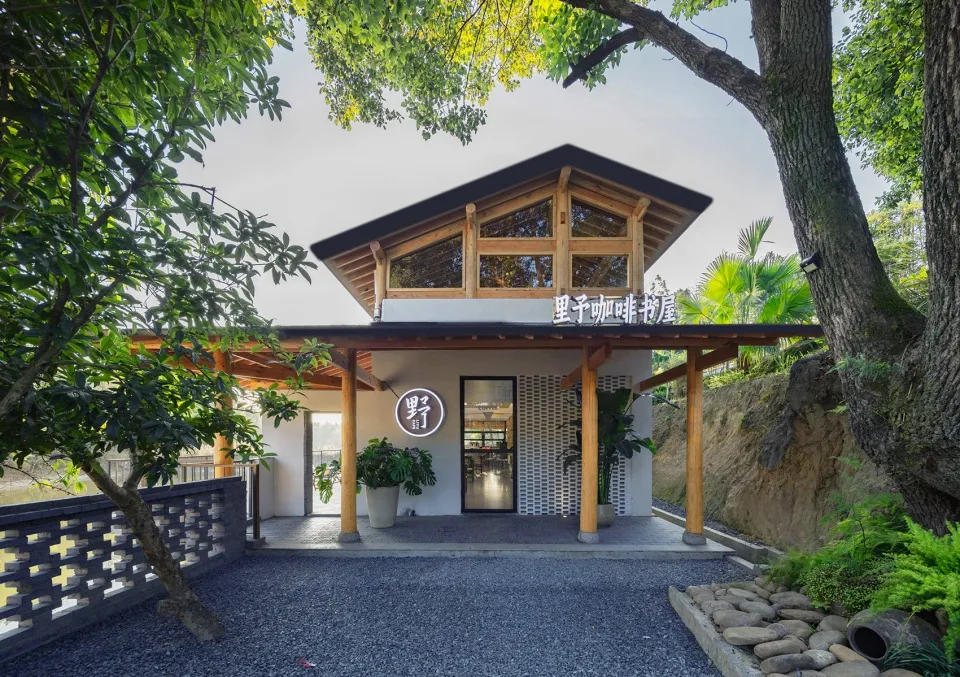 Minimalist cafe exterior with wooden framing, concrete columns, and terrazzo floor.