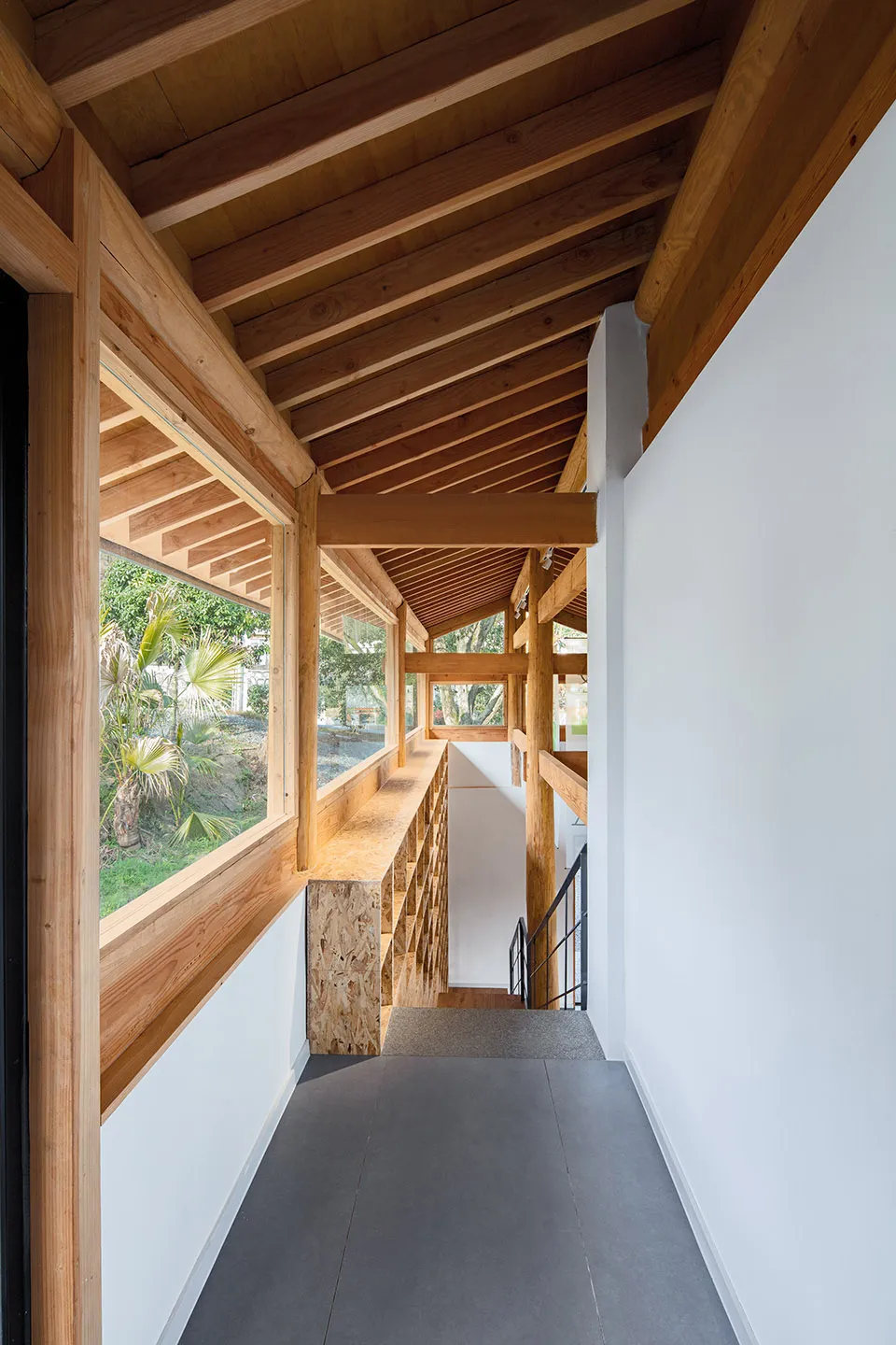 Interior of a modern house featuring wooden beams and concrete flooring.