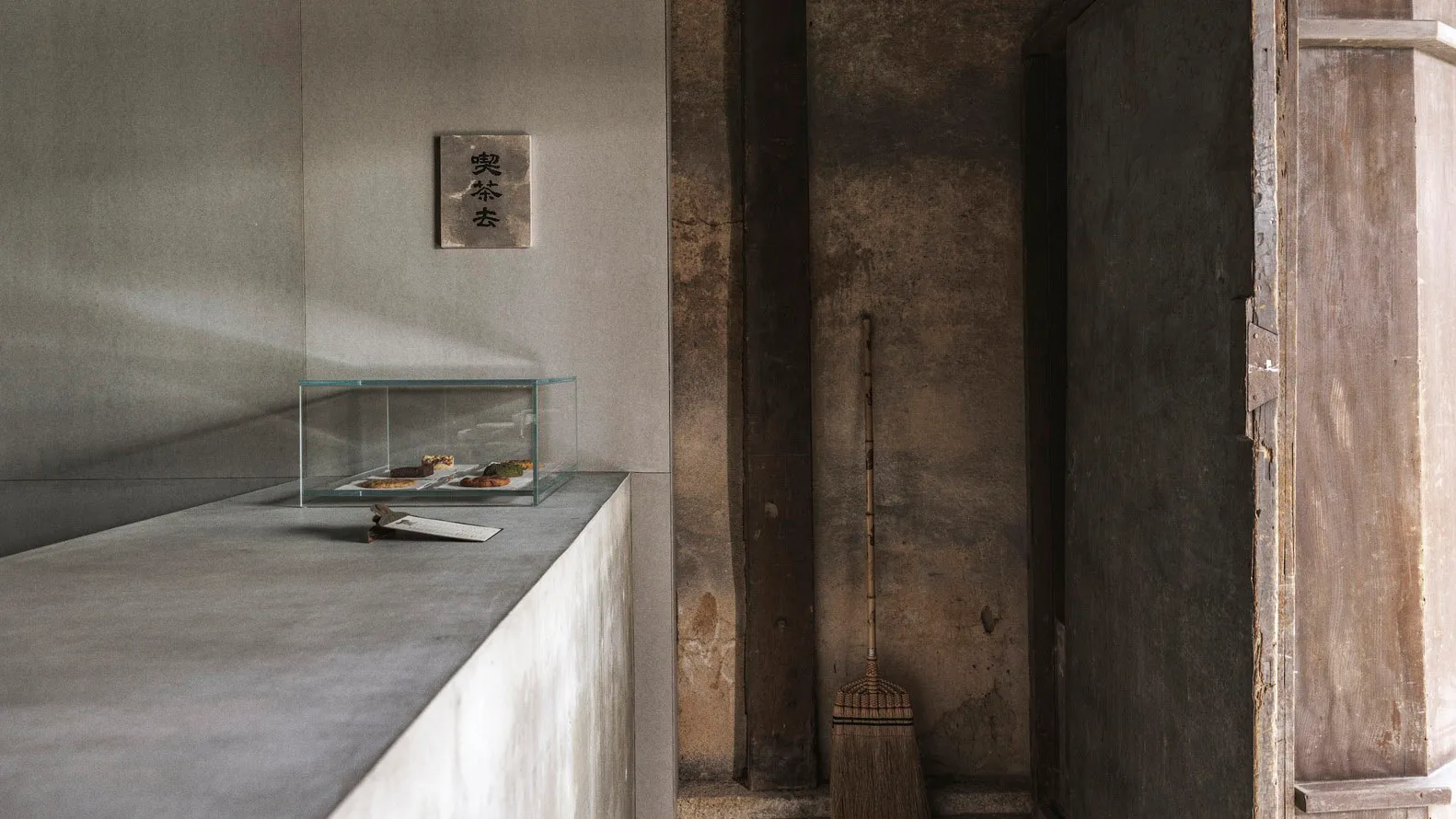 Minimalist interior design featuring a concrete wall with a glass box containing food items.