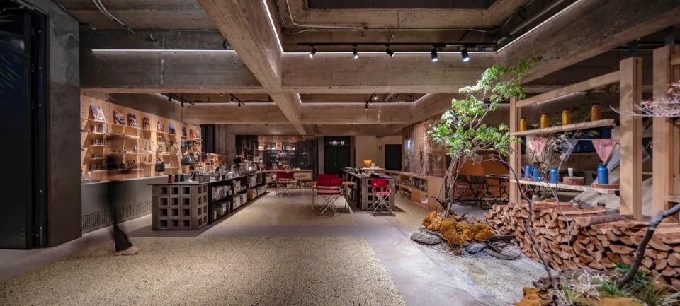 Industrial commercial interior space with exposed concrete ceiling and walls, concrete flooring, and modern furniture.