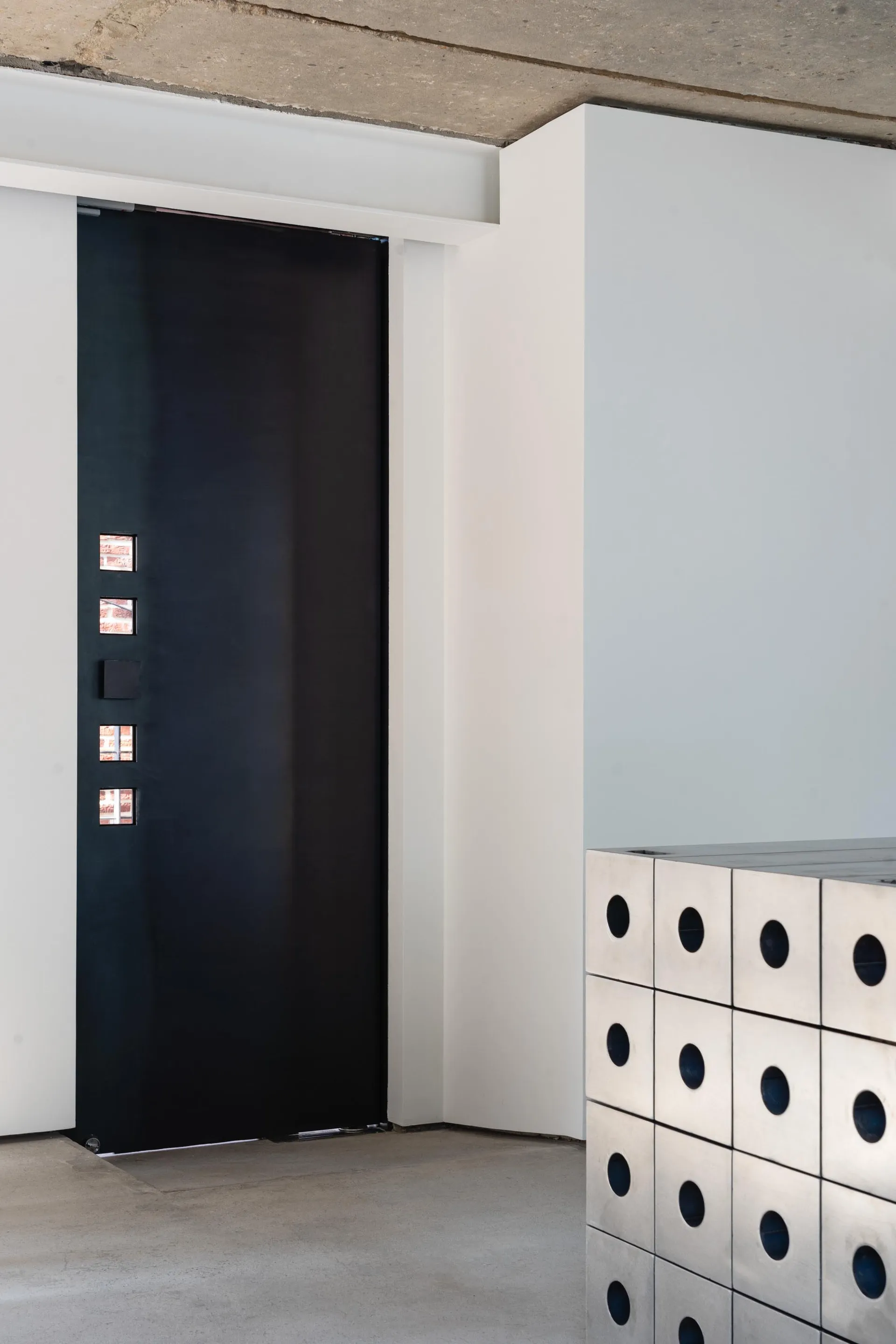 A minimalist interior design featuring a modern metal dresser with circular cutouts.
