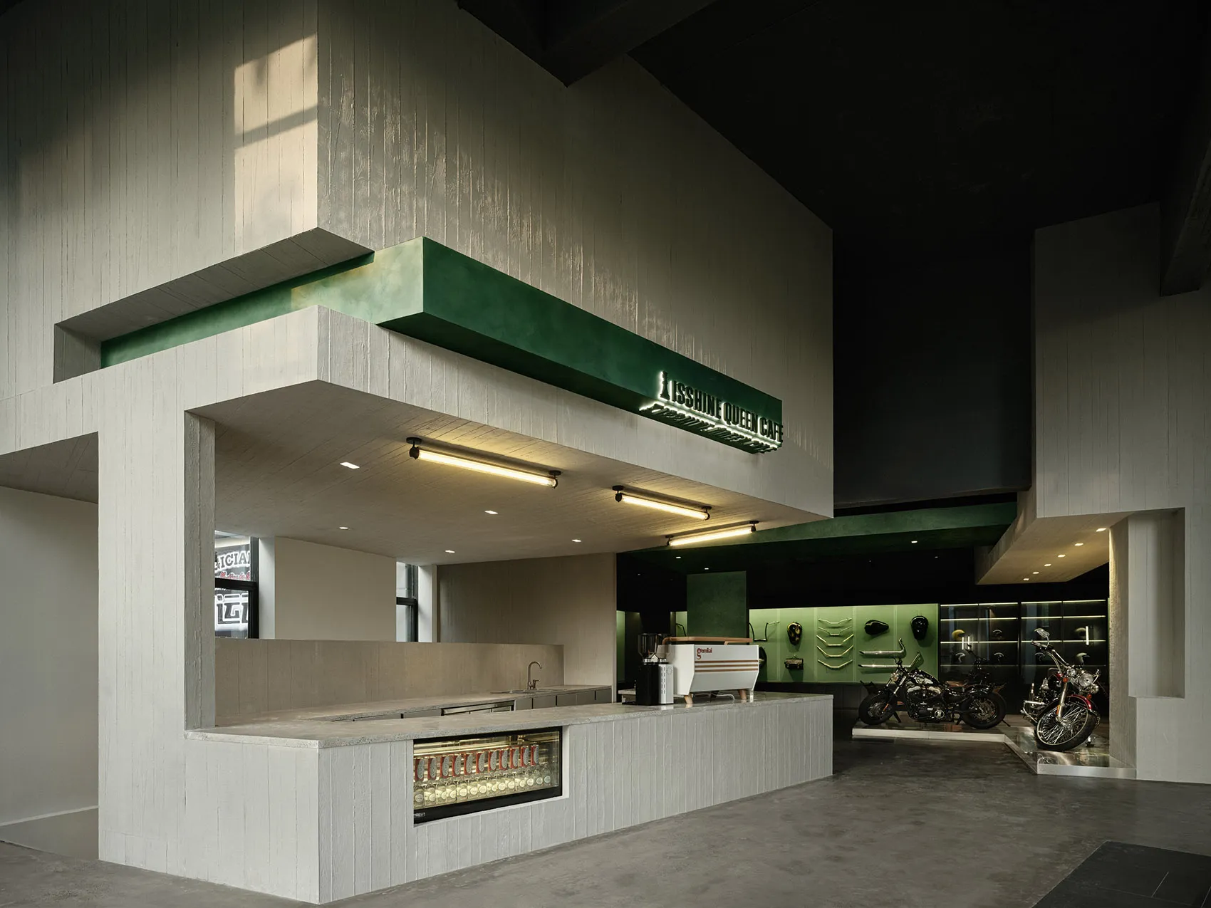 A sleek, minimalist coffee shop interior with concrete walls and a counter.