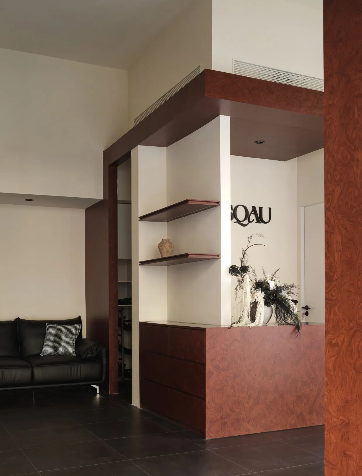 A modern office reception area featuring wood, leather, and fabric elements.