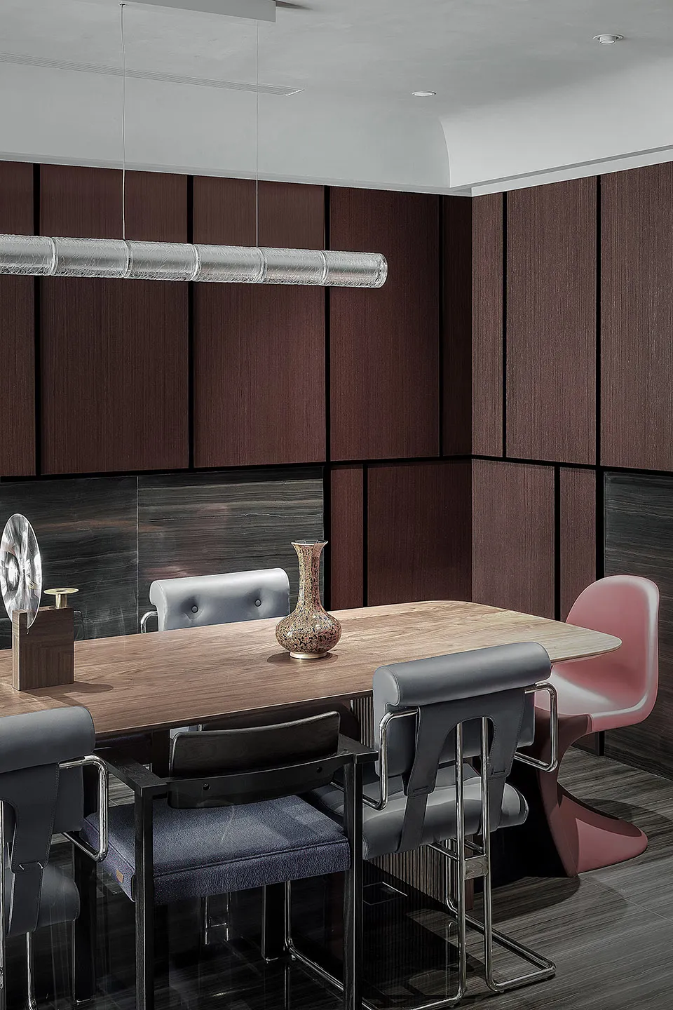 A modern dining room featuring wooden furniture including a rectangular table and various chairs around it.